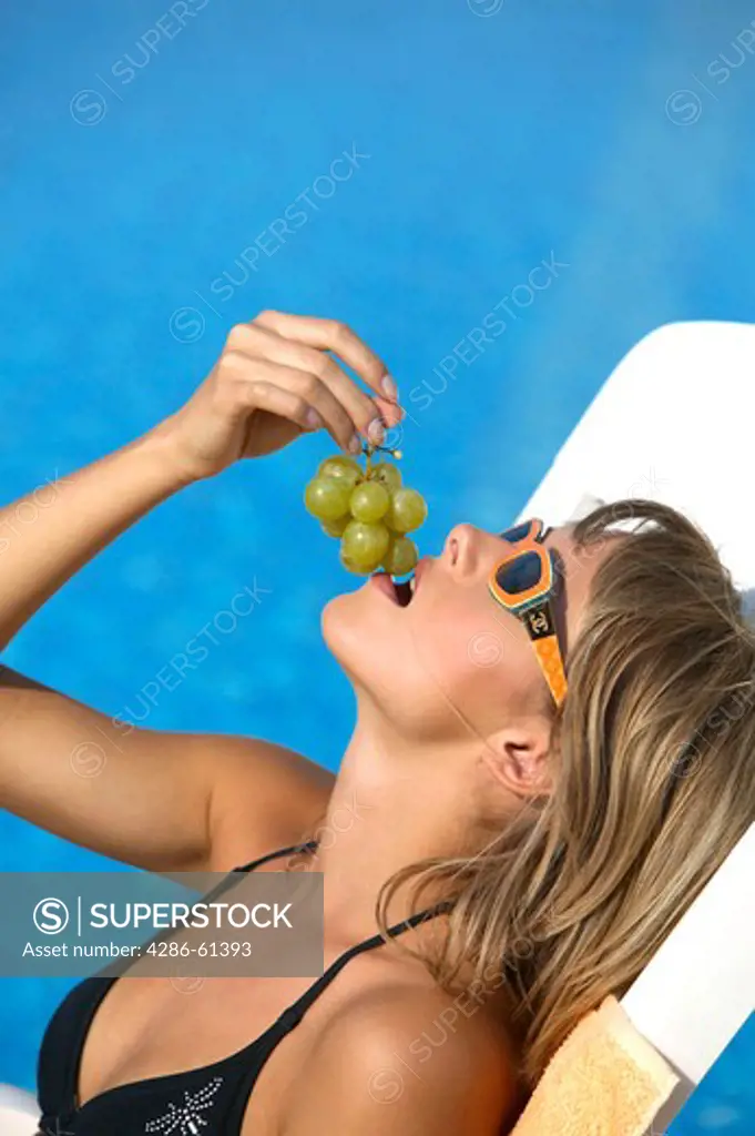 woman eating grapes near the pool