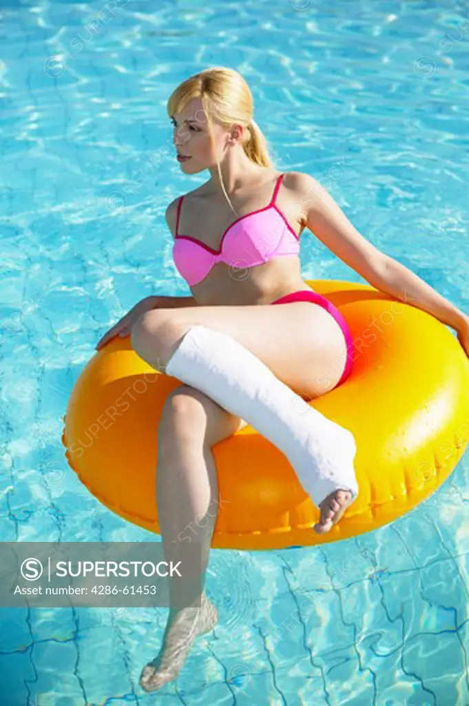 woman with leg in cast on a rubber tyre in the pool