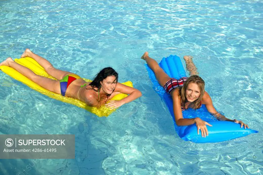 two women having fun with air mattress in the pool