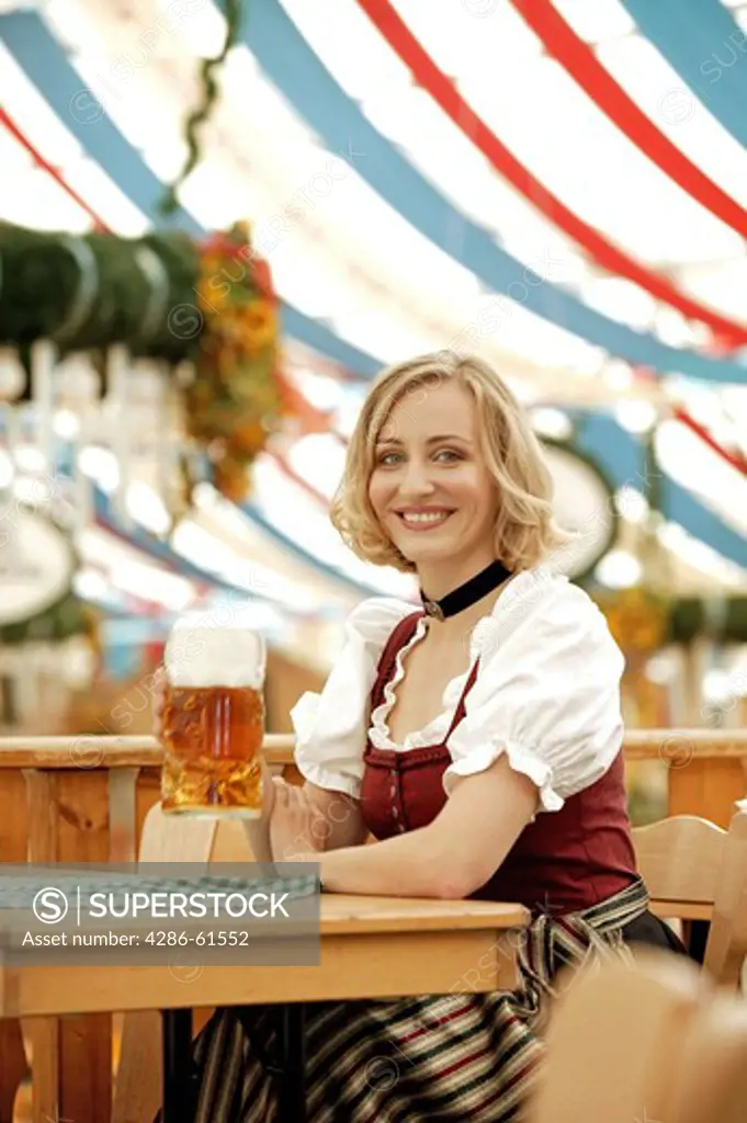 blonde woman in traditional clothes sitting in beer tent