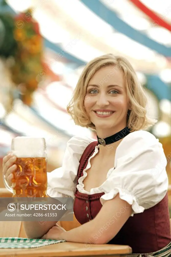 blonde woman in traditional clothes sitting in beer tent