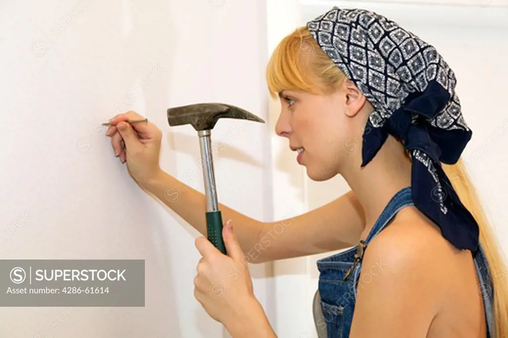 young  woman driving nail into wall
