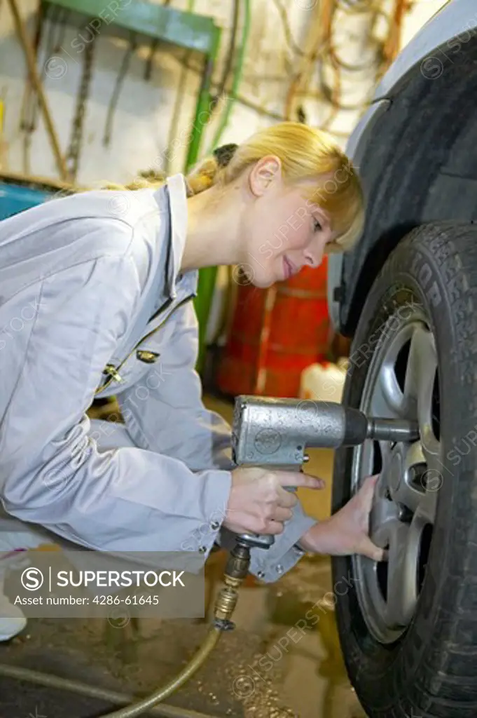 female motor mechanic changing car wheel