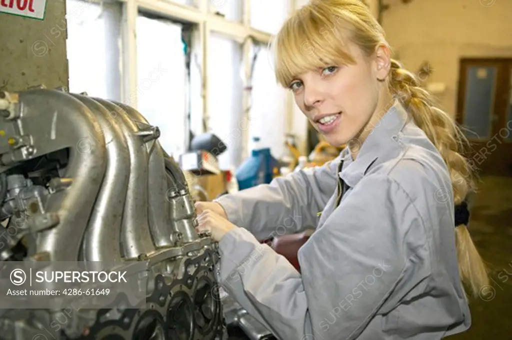 female motor mechanic working on the car motor