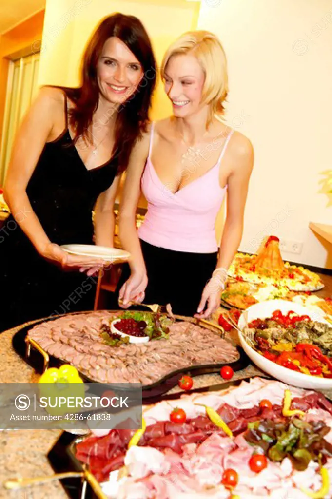 two woman taking from buffet