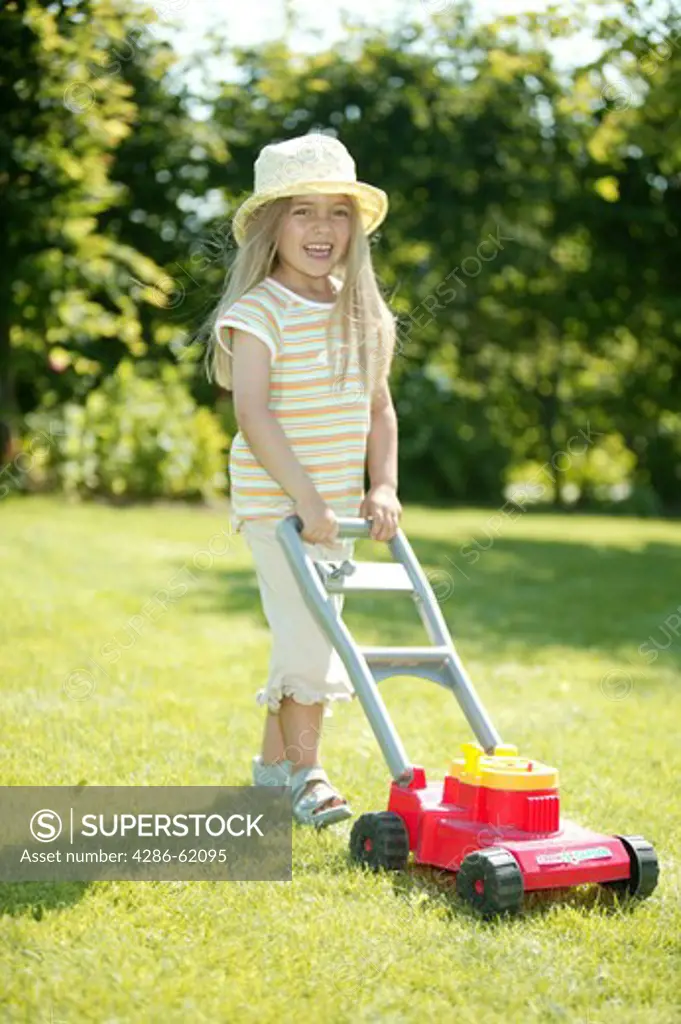 Girl in the garden with toy lawn mower