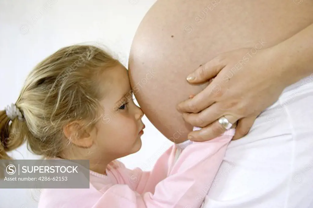 little girl on the belly of her pregnant mother