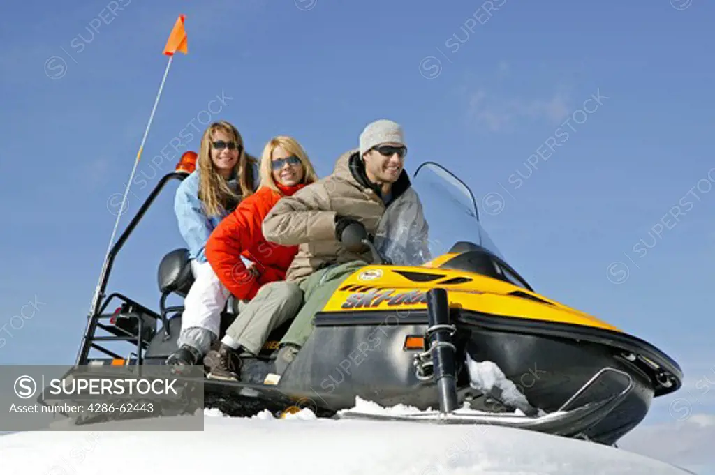 Two Women and Man on Ski Scooter Winter Holiday