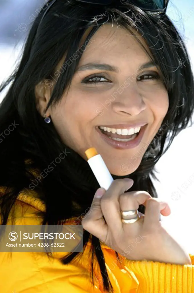 winter holiday woman putting sun cream on her lips