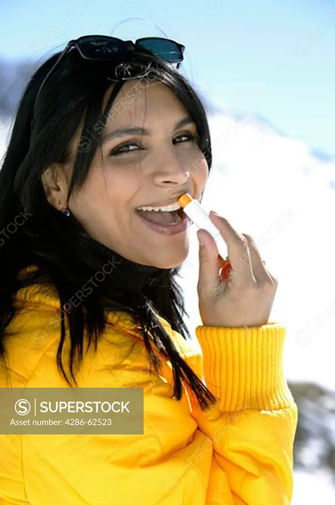 winter holiday woman putting sun cream on her lips