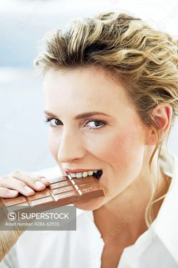 young woman eating big bar of chocolate