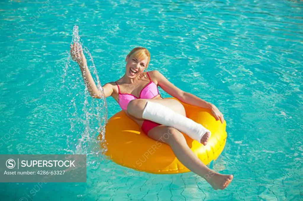 woman with leg in cast on a rubber tyre in the pool