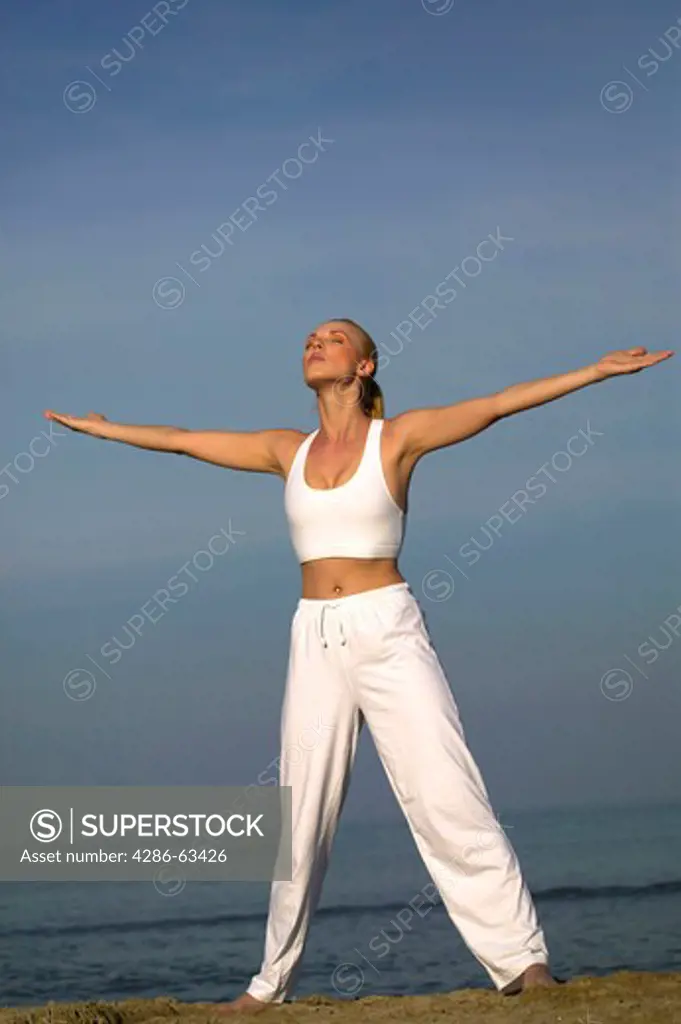woman exercising yoga on the beach