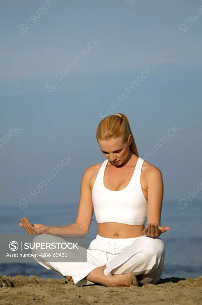 woman exercising yoga on the beach