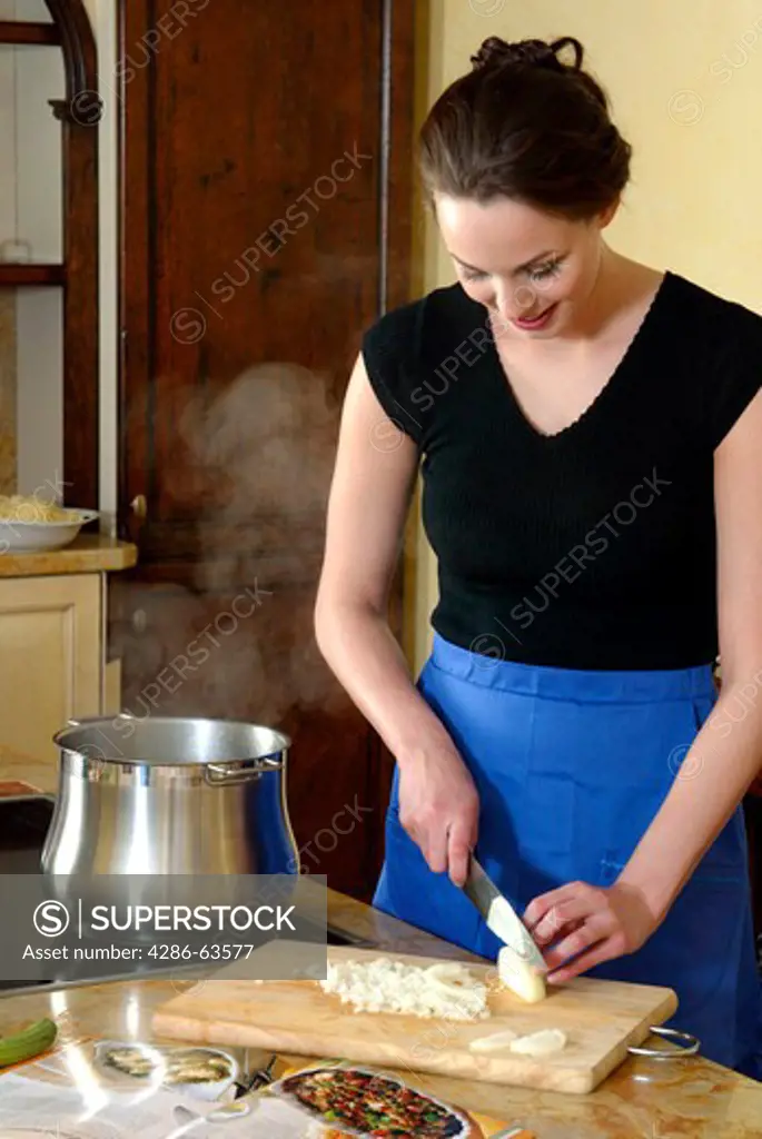 Woman Cutting Onion in a Kitchen Cooking