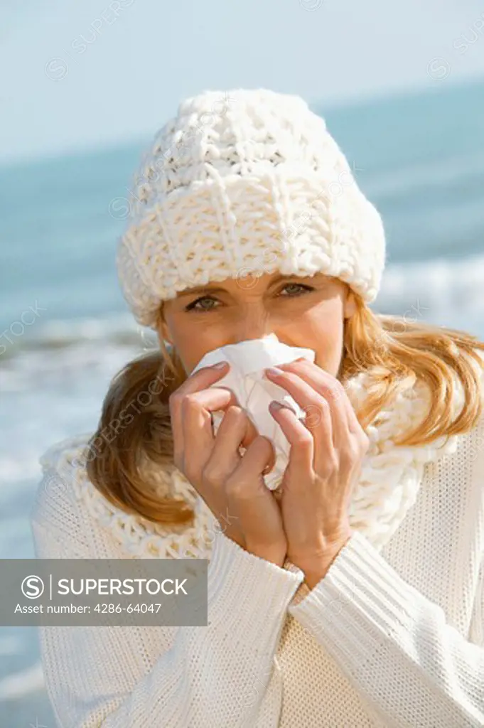 blonde woman by the sea having a cold