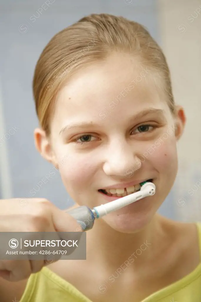 girl brushing her teeth with electric toothbrush