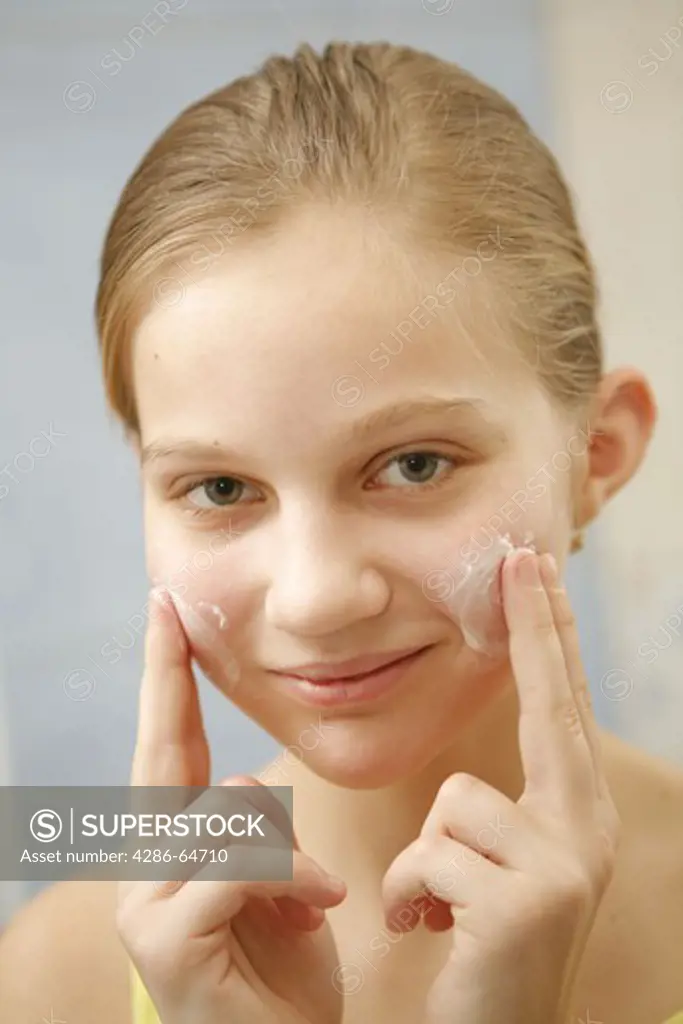 Young girl applying creme on face