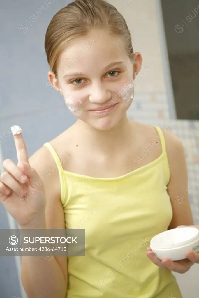 Young girl applying creme on face
