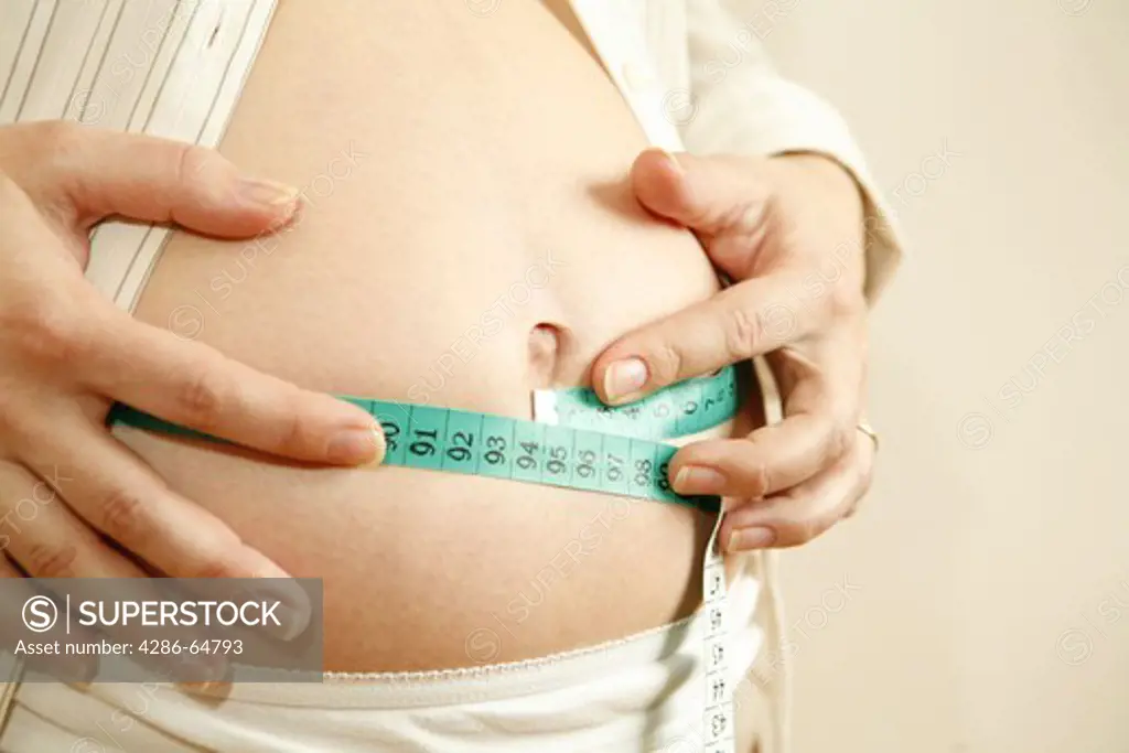 Pregnant woman misses her naked belly with a dimension tape