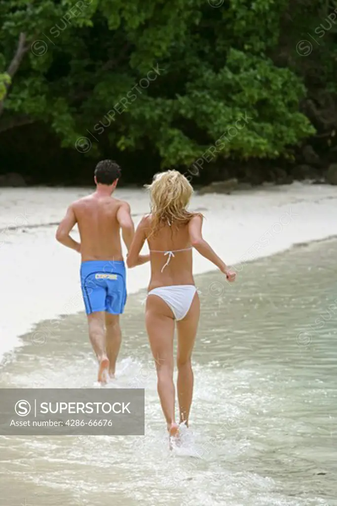Couple in love jogging at tropical beach in