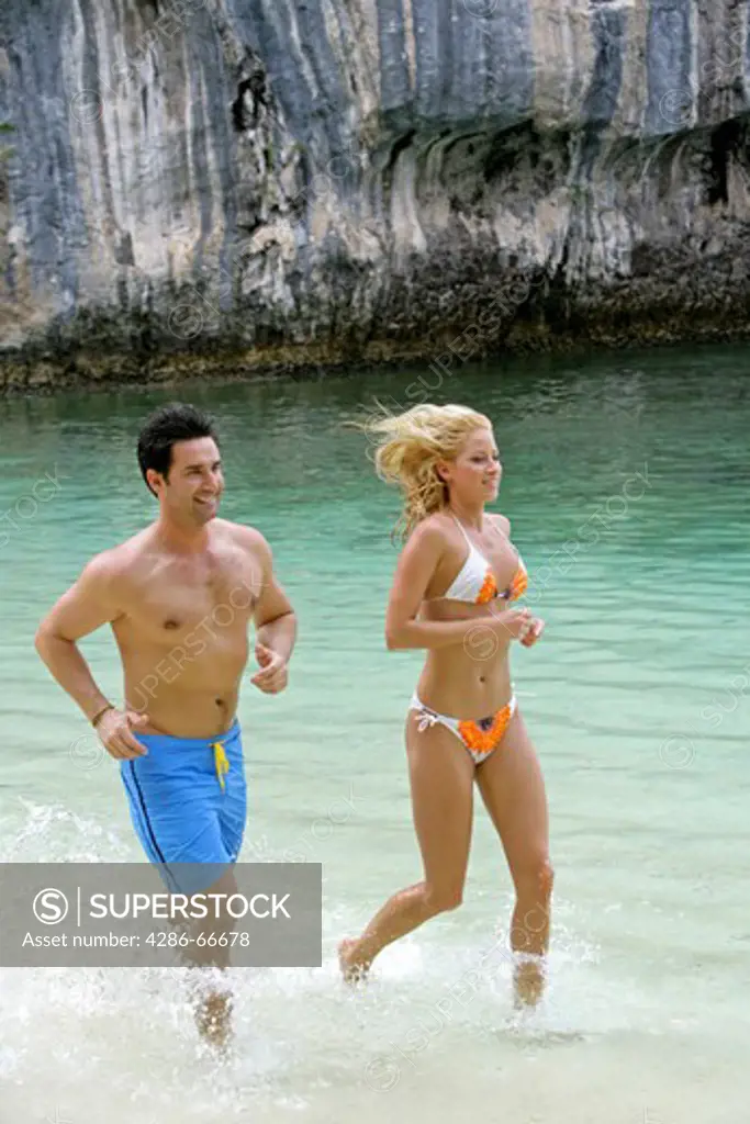 Couple in love jogging at tropical beach in