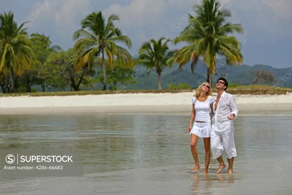 couple in love walking at tropical beach in