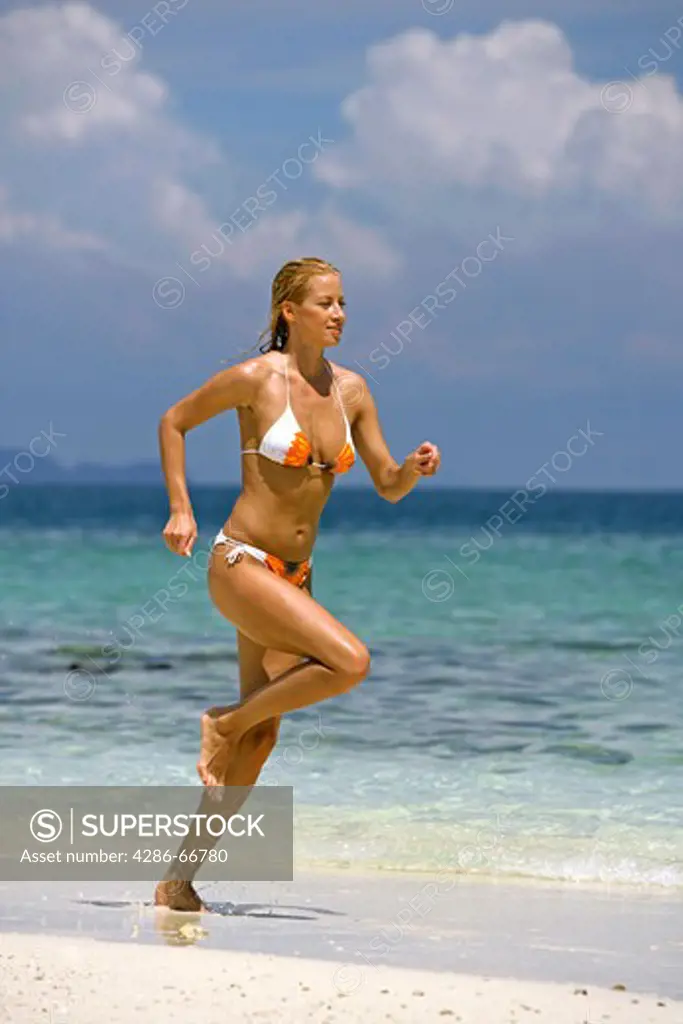 sexy blond woman jogging on tropical beach in  Krabi