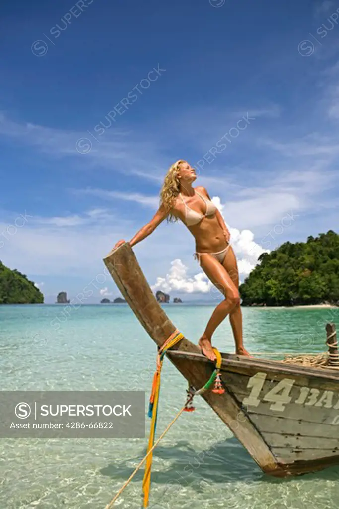 sexy young blonde woman posing on longtail boat in