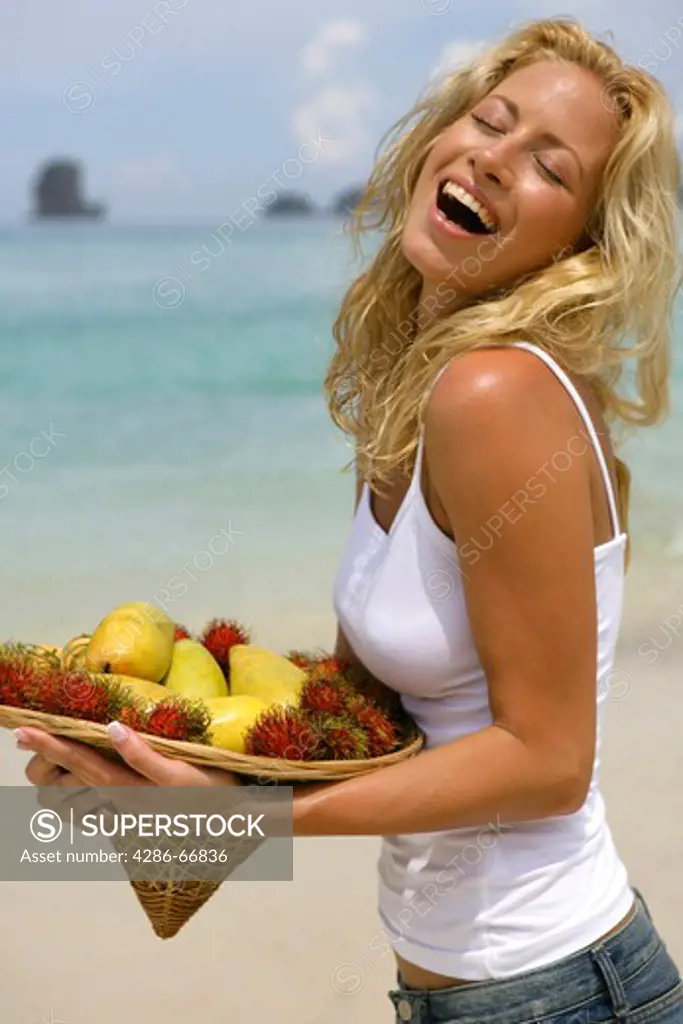 young blond woman on beach with tropical fruits in  portrait