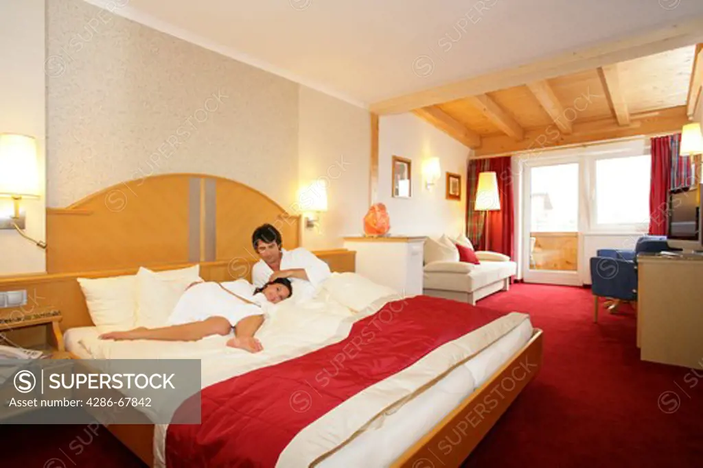 Couple wearing robes in hotel room relaxing