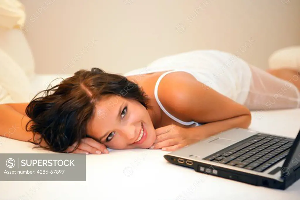 Young woman tired on bed with laptop