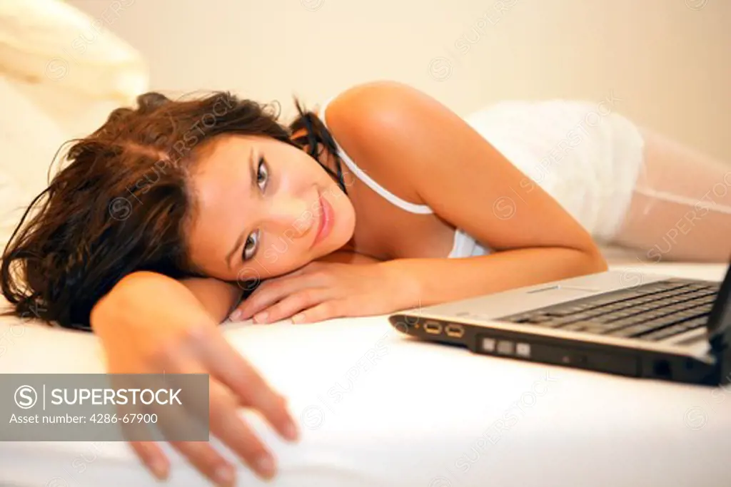 Young woman tired on bed with laptop