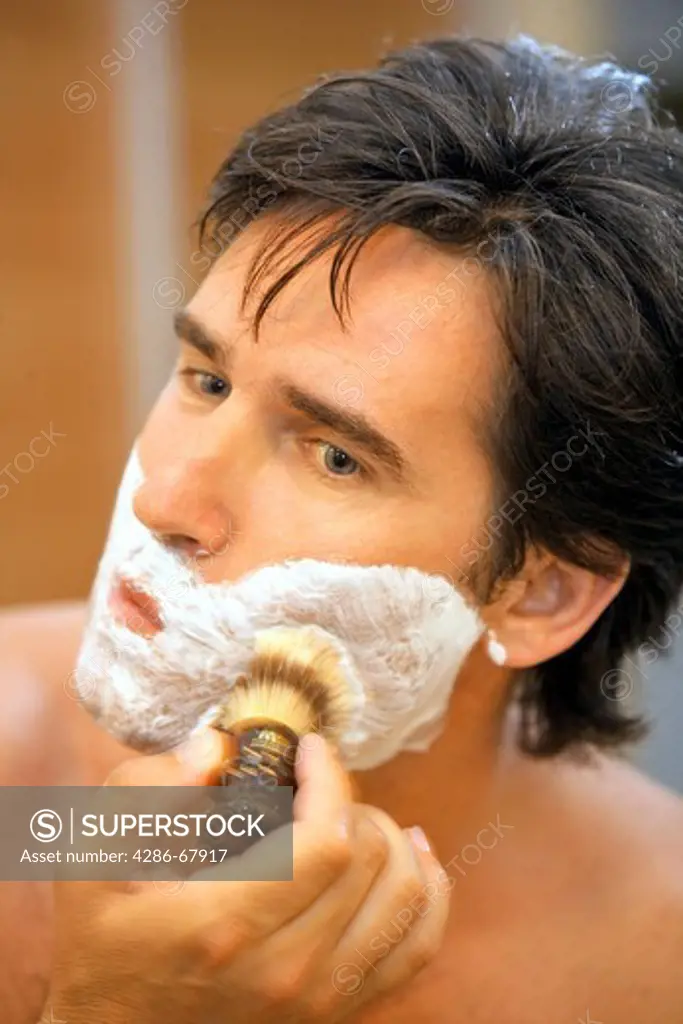 Young man rubbing shaving cream on face portrait