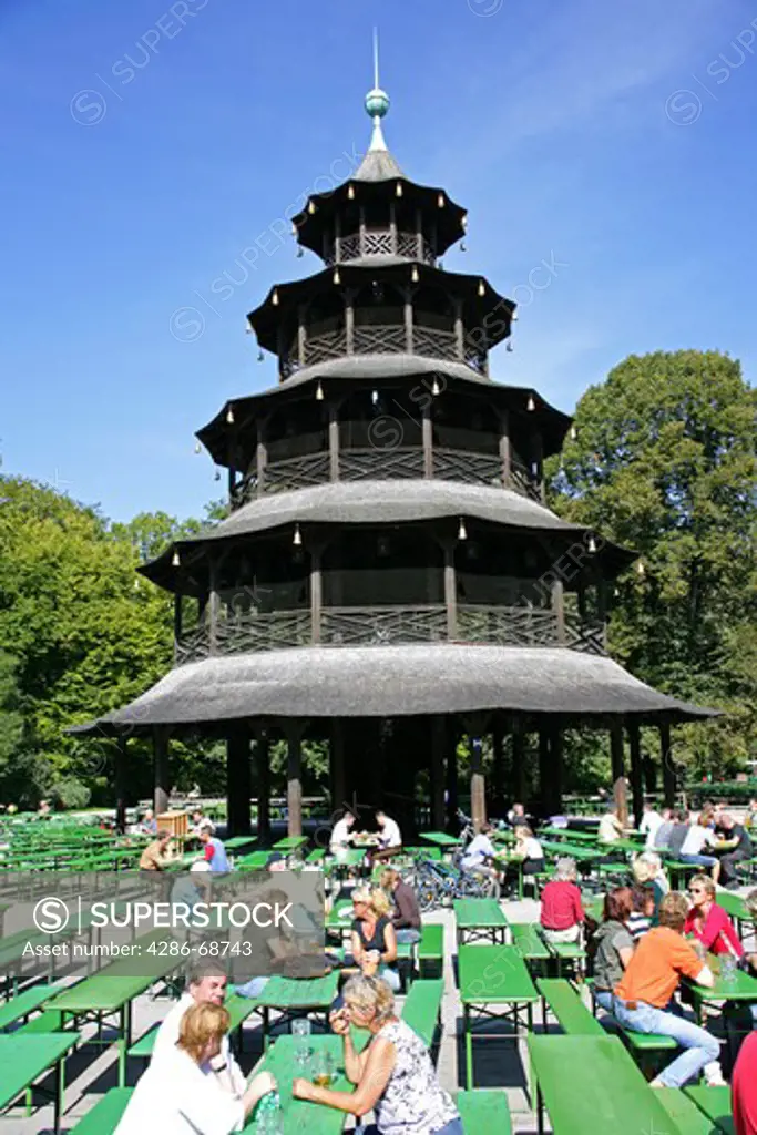 Germany Bavaria Munich people sitting at the Chinese Tower beer garden in the Englischer Garten