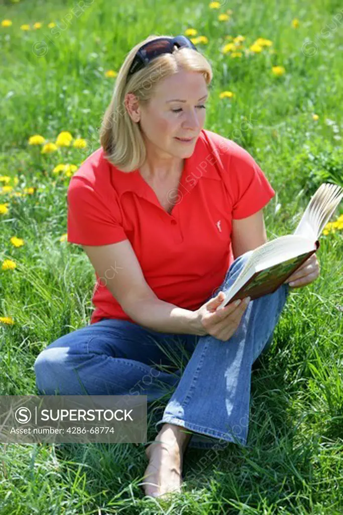 Mature woman reading book outside in garden