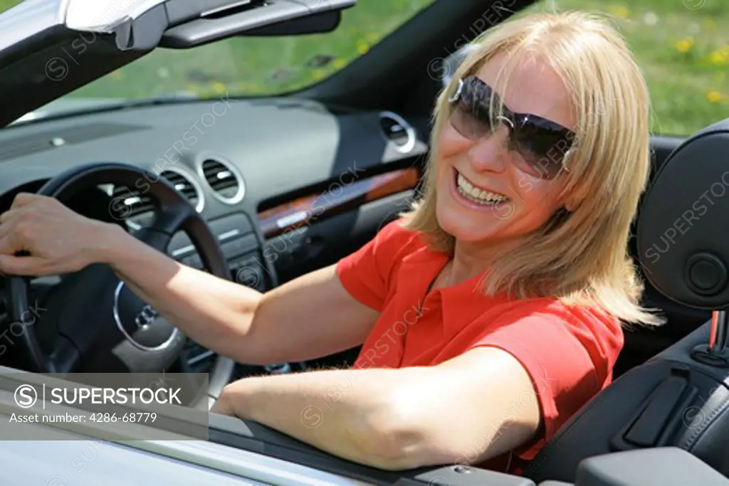 A senior woman driving cabriolet sportscar with roof down