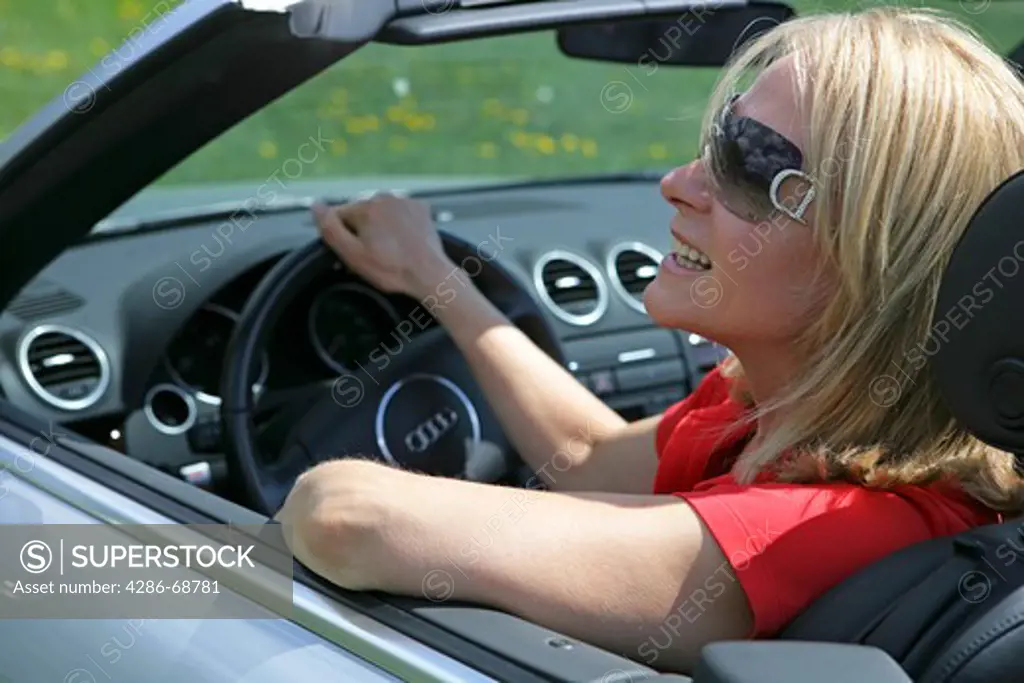 A senior woman driving cabriolet sportscar with roof down
