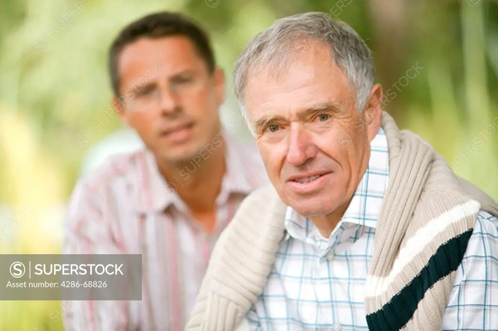 Elderly father and adult son in garden