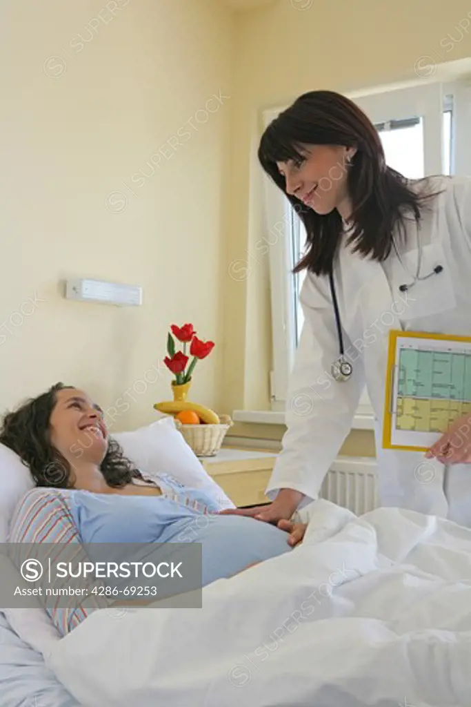 doctor checking pregnant woman lying on hospital bed