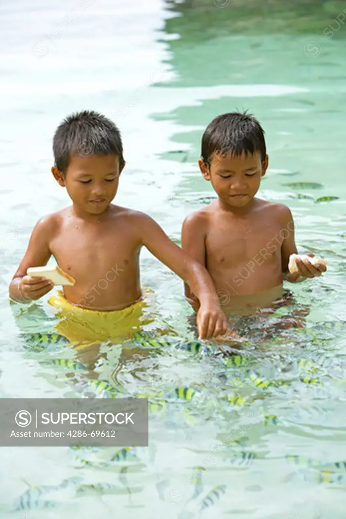 Thai children feed fishes in andaman see near Krabi