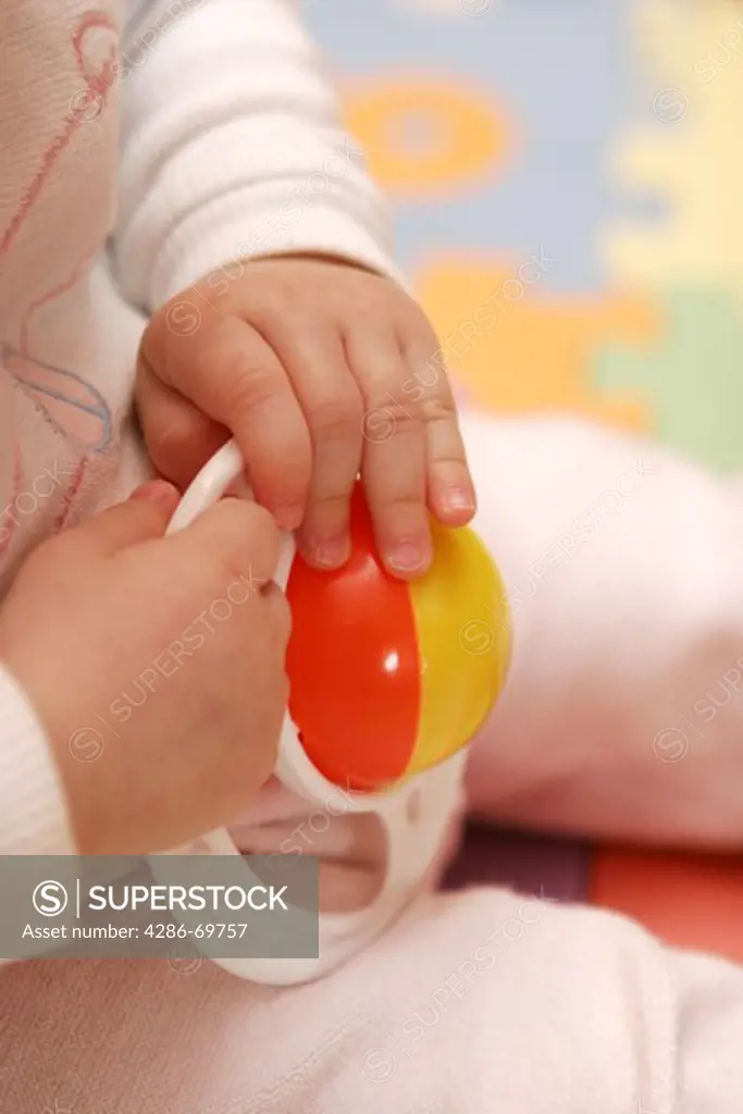 Baby hand reaches for a Spiezeug