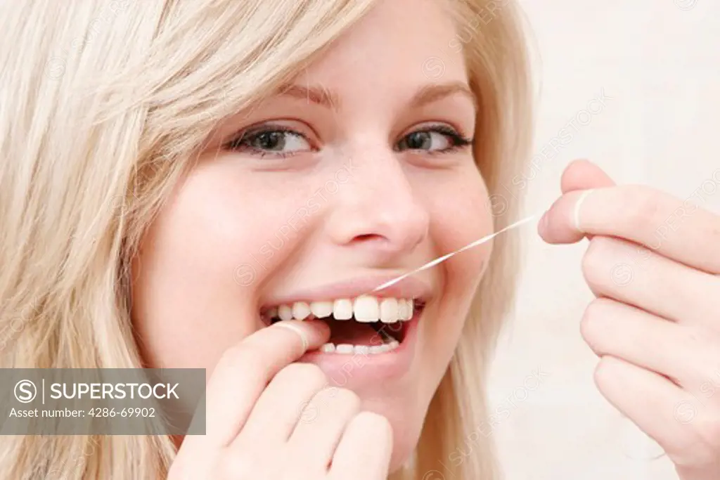 Young woman cleans to herself the teeth with dental floss