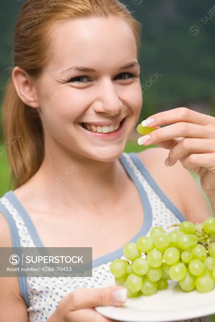 Young pretty woman eating fresh green grapes.