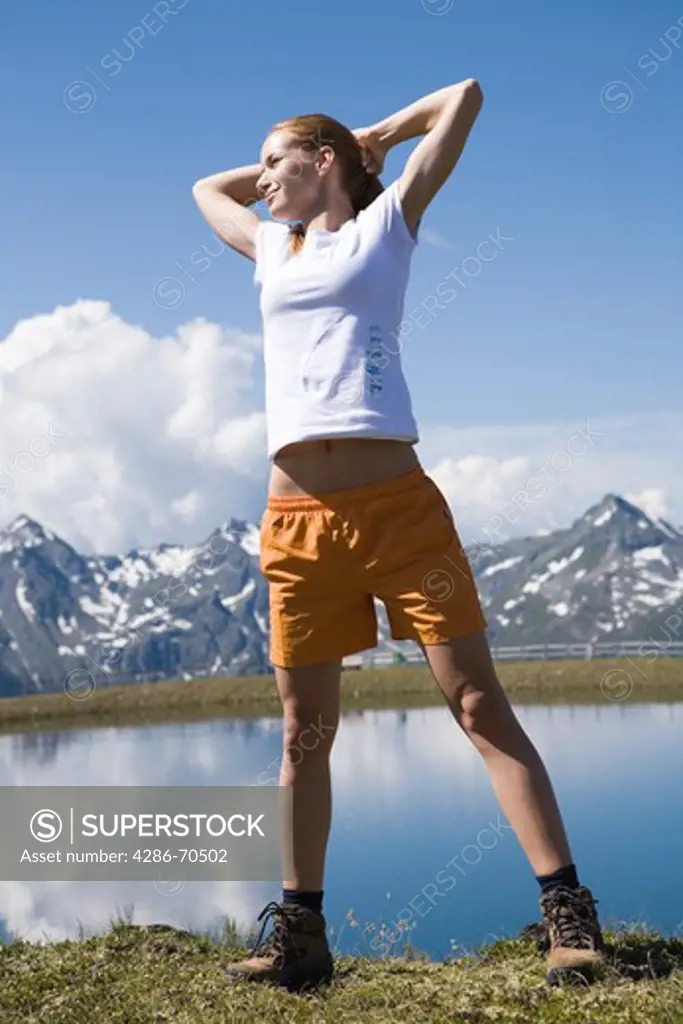 Young woman stretching back in the mountains.