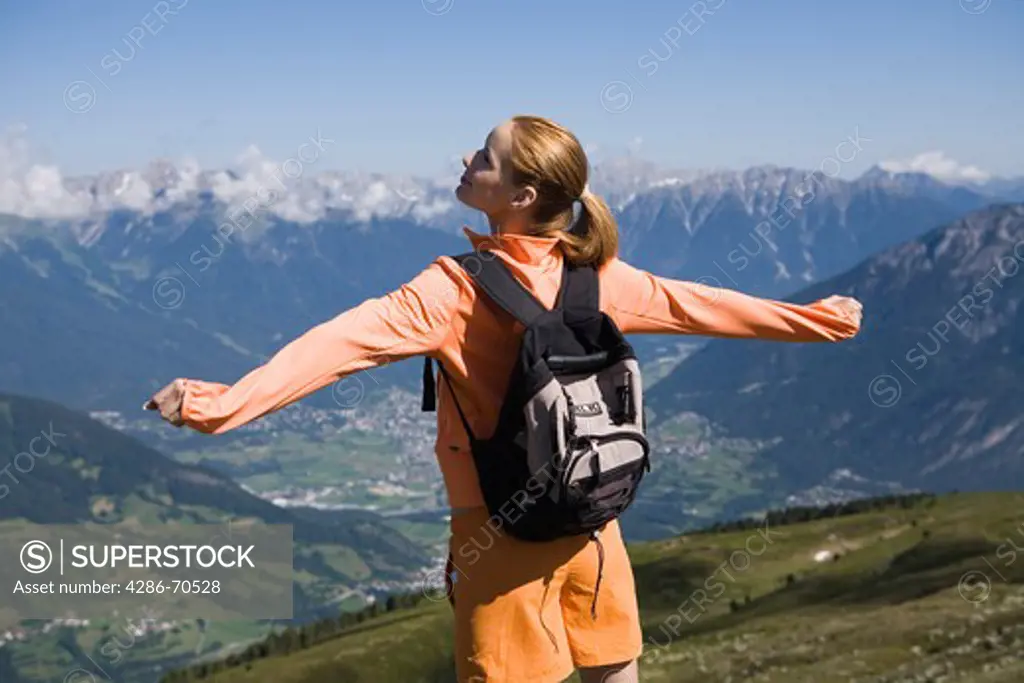 Young woman stretching back and breathing in the mountains.