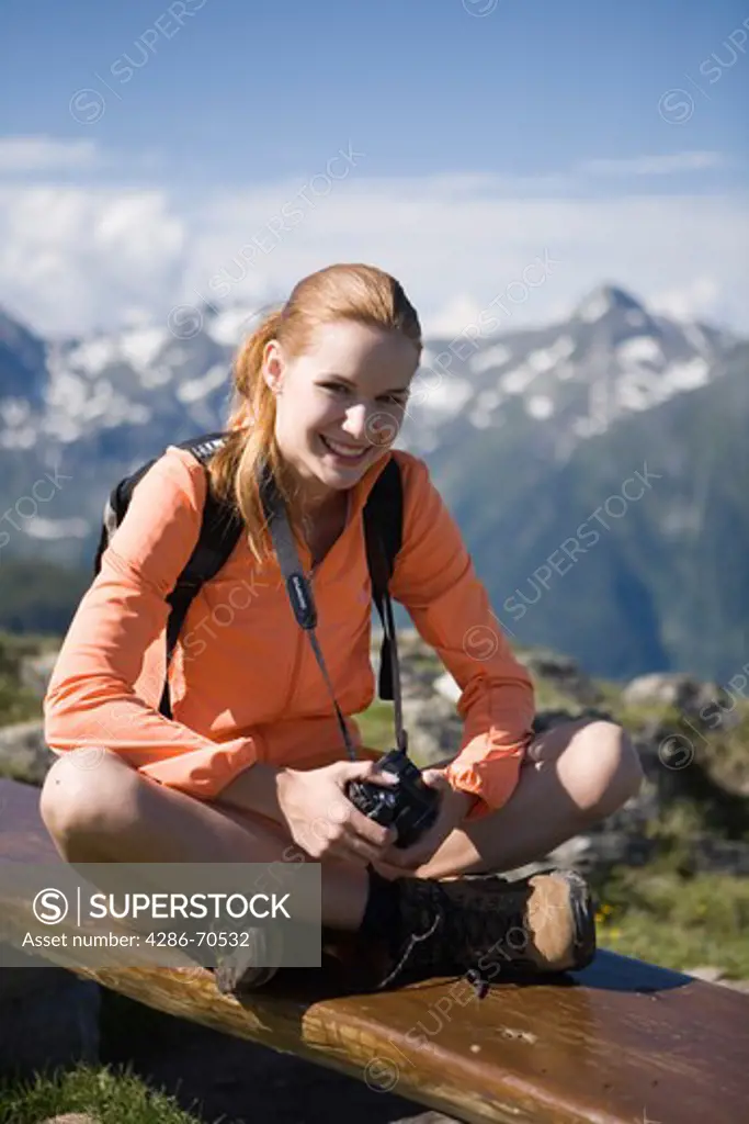 Pretty young woman trekking in the mountains and having rest.