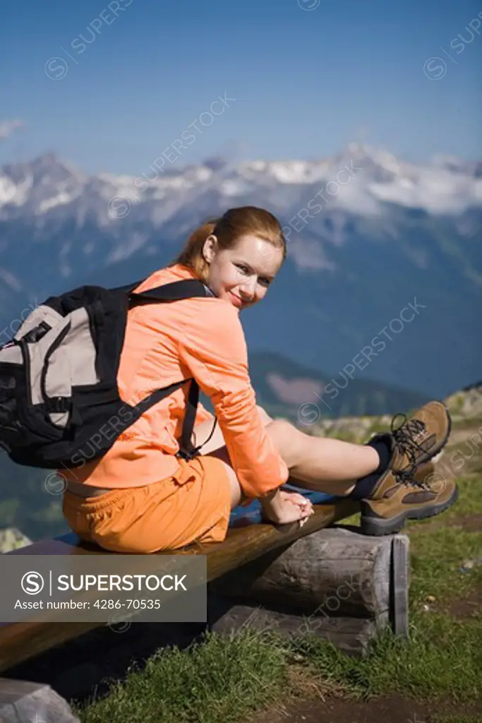 Pretty young woman trekking in the mountains having rest.