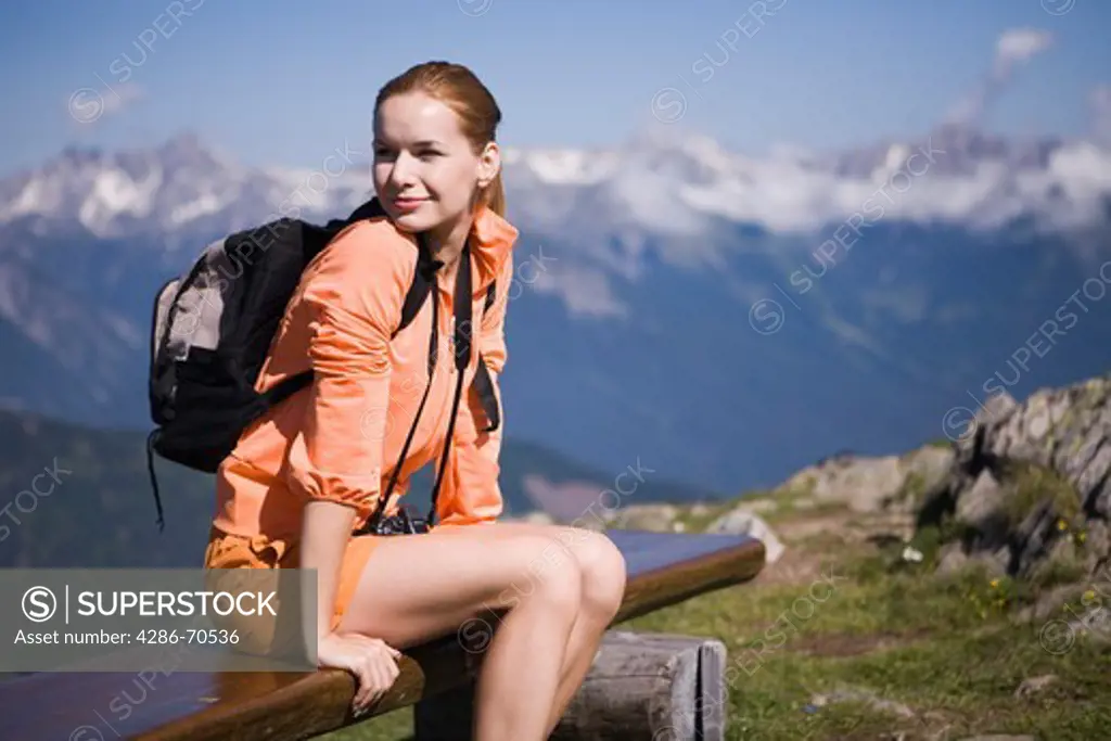 Pretty young woman trekking in the mountains having rest.