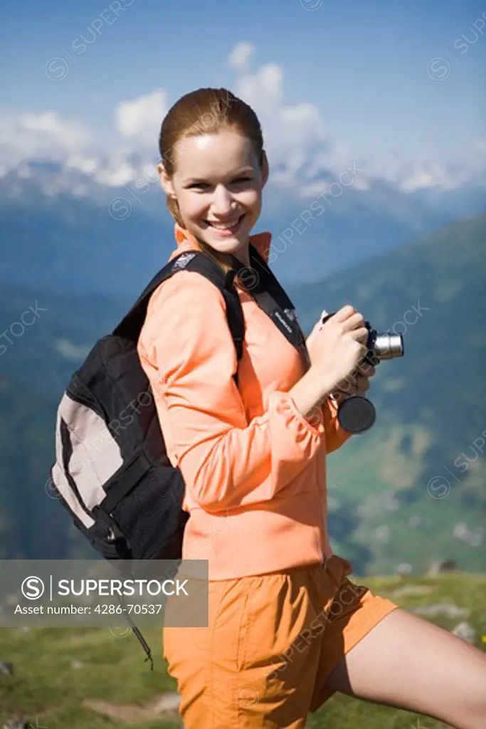 Pretty young woman trekking in the mountains and taking pictures.